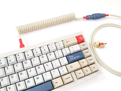 beige keyboard cable for GMK Soyamilk  keycaps. With cream coil, polar blue Gx16 Aviator and red hea-shrink on a white keyboard with Soyamilk keycaps.