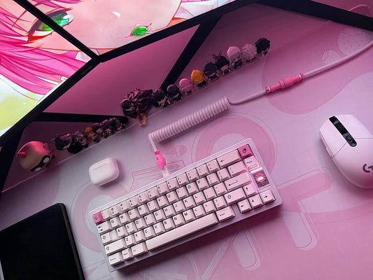 Pink coiled keyboard cable on pink deskmat and mechanical keyboard with pink keycaps.